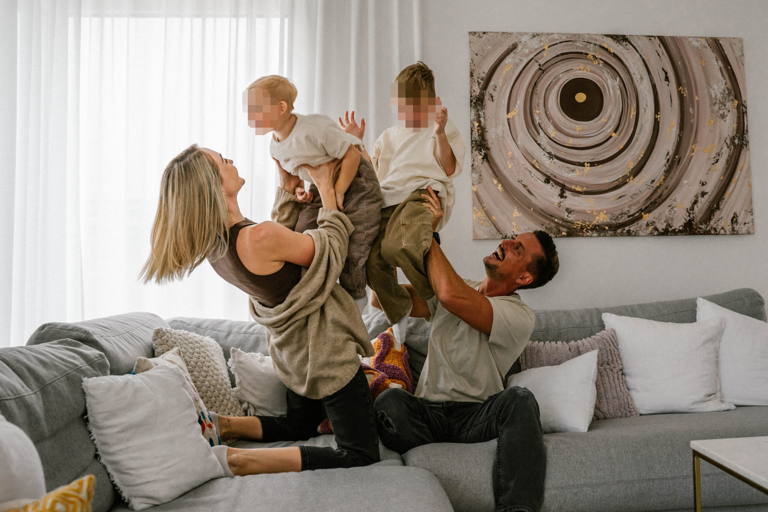 Vierköpfige Familie sitzt auf der Couch und hat Spaß.